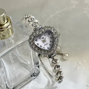Nahaufnahme Detail einer charmanten herzförmigen Strass-Quarzuhr mit elegantem Perlenarmband.