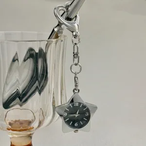 Detailaufnahme einer metallischen Stern Taschenuhr als Schlüsselanhänger am Glas.