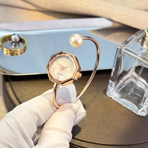 Vista detallada del reloj pulsera de perlas para mujer con esfera octagonal y brazalete abierto.