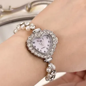 Nahaufnahme der herzförmigen Strass-Quarzuhr mit doppeltem Perlenarmband für elegante Looks.