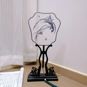 Traditional Chinese embroidered fan with black wooden stand and tassel, ancient style decor.
