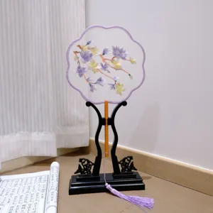 Chinese embroidered round fan detail, elegant floral pattern with purple tassel and wood stand.