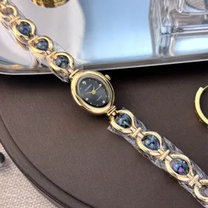 Dettaglio squisito di orologio al quarzo ovale, elegante cinturino dorato con accenti colorati.