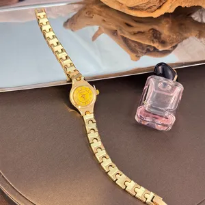 Detail shot of a delicate gold quartz watch featuring a small yellow dial and fine metal link bracelet.