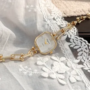 Primo piano dettagliato di un elegante orologio al quarzo dorato quadrato con cinturino a catena.