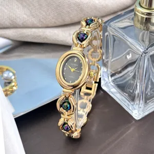 Dettaglio di elegante orologio al quarzo ovale dorato con bracciale a maglie e perline colorate.