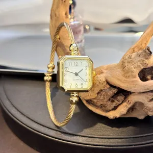 Nahaufnahme Detail der goldenen Kabel Armband Quarzuhr mit elegantem quadratischem Zifferblatt.