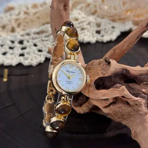 Nahaufnahme einer Vintage Damen Quarzanduhr mit Tigerauge Perlenarmband und weißem Zifferblatt.