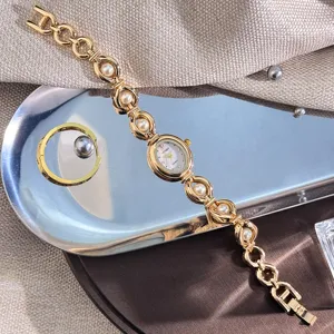 Dettaglio orologio donna ovale vintage con cinturino in perle finte, elegante segnatempo al quarzo oro.