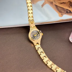 Close-up of a delicate gold quartz watch with a fine link strap and minimalist black dial.