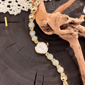 Nahaufnahme Detail der goldenen Damenarmbanduhr im Vintage-Stil mit grünen Steinperlen.