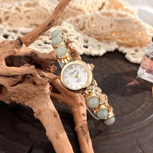 Nahaufnahme einer Vintage Damen QuarzUhr mit grünem Perlen Armband und goldenem Gehäuse.