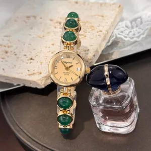 Detailaufnahme einer Damen Quarz Armbanduhr mit gruenen Perlen und edlem Zifferblatt.