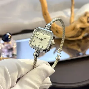 Nahaufnahme Detail der Damenuhr mit quadratischem Zifferblatt und Stahlseilarmband.