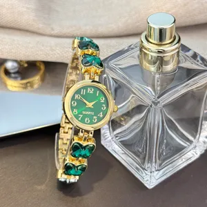 Detailansicht einer goldenen Damen Quarzuhr mit grünem Schmetterling Kristall Armband.