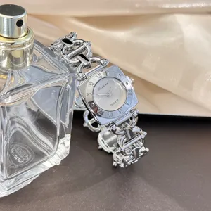 Detailaufnahme einer eleganten Damen Quarzuhr mit quadratischem Zifferblatt und Metallkette.