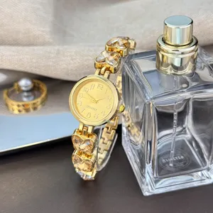 Detailansicht der goldenen Damenuhr mit Quarzwerk, Kristall-Herz-Armband und Glasflakon.