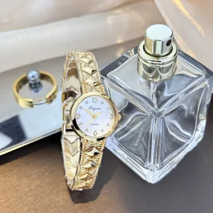 Nahaufnahme Detail der goldenen Quarzarmbanduhr mit geflochtenem Metallarmband und Parfum.