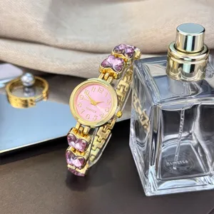 Exquisites Damen Quarzuhr Detail mit rosa Zifferblatt und lila Kristall Schmetterlingen.