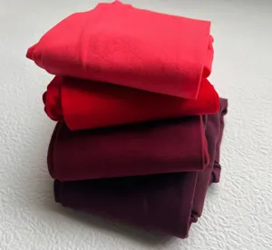 Close-up of matte velvet colored tights stacked, showing soft texture and shades of red.