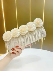Nahaufnahme der eleganten Abendtasche mit Stoffrosen und glänzenden Strass-Fransen.