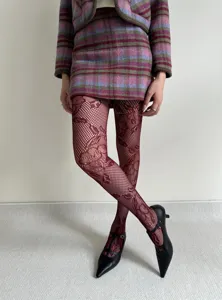 Detailed shot of burgundy floral lace fishnet tights paired with chic plaid skirt set and shoes.