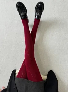 Gros plan sur des collants bordeaux pour femmes à motif losanges délicat et style élégant.