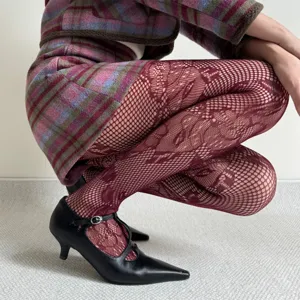 Detailed shot of burgundy floral lace fishnet tights paired with black Mary Jane low heels.