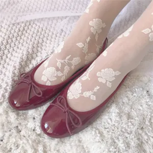 White sheer pantyhose featuring delicate rose embroidery, paired with chic red flat shoes.