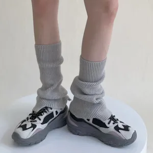 Detalle de calentadores de punto gris que muestran calcetines de invierno y zapatillas de deporte.