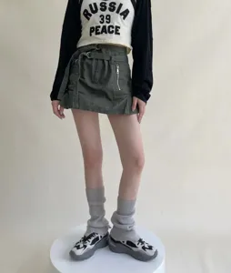 Detalle de calentadores de moda combinados con minifalda elegante y parte superior estampada.
