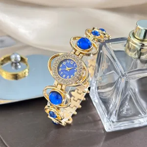 Gold tone women's quartz wristwatch with blue gemstone links and rhinestone bezel detail.
