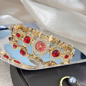Women fashion quartz watch with red crystal stones and gold alloy bracelet band detail.