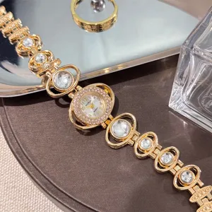 Detailed view of gold-tone women quartz watch with rhinestone crystal links and decorative band.