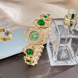Detailed shot of luxury gold women watch with green stones and sparkling rhinestones accent.