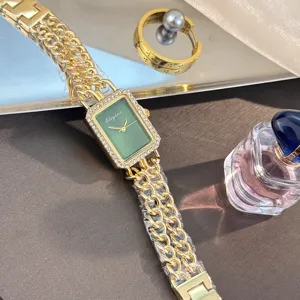 Detailaufnahme der grünen rechteckigen Strass-Quarzuhr mit goldenem Kettenarmband.