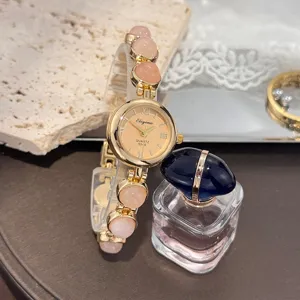 Detailaufnahme einer Vintage Damenuhr mit Quarzwerk, rosa Perlenarmband und goldenem Zifferblatt.