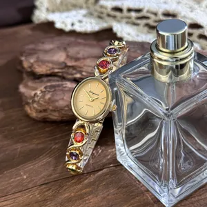 Exquisite vintage oval quartz watch with colorful gem inlaid bracelet and gold dial design.