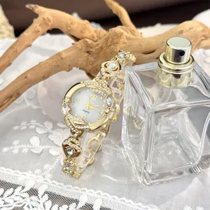 Detalle de reloj de cuarzo dorado para mujer con pulsera de diamantes de imitación y nácar.
