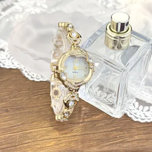 Reloj de cuarzo dorado de lujo para mujer con pulsera de diamantes de imitación y esfera nácar.