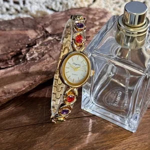 Detailed shot of gold quartz women watch, colorful gemstone accented strap, elegant design.