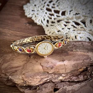 Vintage gold quartz watch detail with colorful gemstones and oval dial on rustic tree bark.