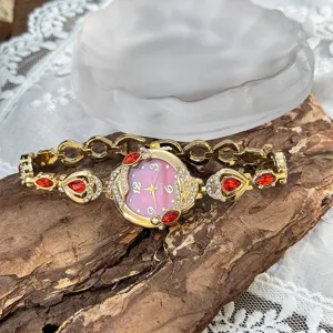 Vista detallada de reloj cuarzo mujer koi con pedrería roja, esfera de nácar y pulsera dorada.