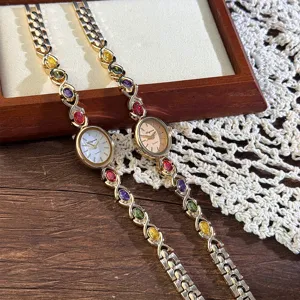Close-up detail of vintage oval quartz watch with colorful gemstone inlay and delicate metal strap.