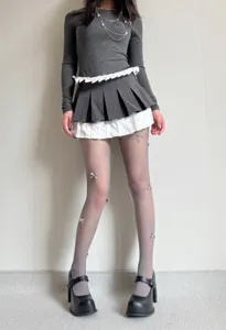 Close-up detail of grey fishnet tights with cute 3D bows, ballet-core style legwear.