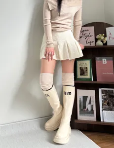 Detail shot of cozy over-the-knee knit socks paired with creamy boots in a lifestyle setting.