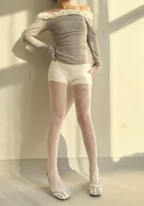Collants en dentelle blanche avec motif résille cœur et diamant, détail de jambe.