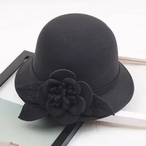 Detail view of black wool felt dome hat featuring an elegant 3D floral accent and leaf.