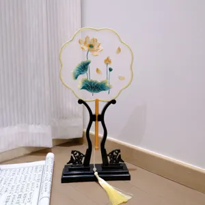 Traditional Chinese embroidered round fan with wooden stand and tassel, elegant decor.
