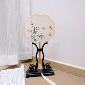 Detailed view of traditional Chinese embroidered round fan with delicate bamboo and butterfly patterns.